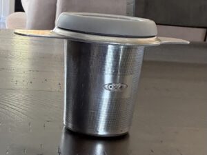 Tea infuser with lid on wooden surface