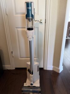 Shark cordless stick vacuum standing on hardwood floor in home